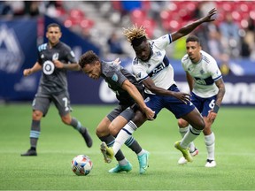 Minnesota United's Hassani Dotson, left, and Vancouver Whitecaps' Leonard Owusu compete for the ball during the first half of an MLS soccer game in Vancouver, Wednesday, Oct. 27, 2021.