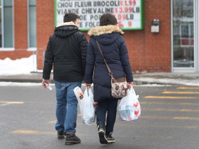 Shoppers carry plastic bags full of groceries.