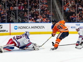 Edmonton Oilers' Connor McDavid scores a late-game goal over New York Rangers goalkeeper Alexandar Georgiev on Friday night.