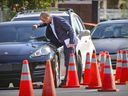 A Montreal police investigator examines a bullet hole in a car at the scene of a shooting in Rivière-des-Prairies on August 2, 2021 that left three people dead and two others injured. 