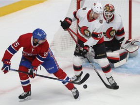 Ryan Poehling of the Montreal Canadiens and Josh Norris of the Ottawa Senators attempt to take control of the puck in front of goalkeeper Anton Forsberg during preseason game in Montreal on October 7, 2021.