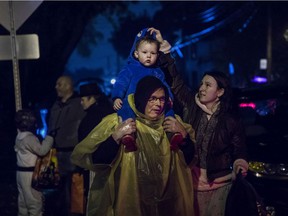 On a rainy Halloween night in Montreal on Sunday, Avery Thompson receives a costume adjustment from mother Jessica Thompson while on the shoulders of her father Gerry Thompson in the Montreal West area.