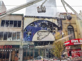 Firefighters pour water into the building containing the former Super Sexe strip club in Montreal on Sunday, Oct. 31, 2021.