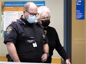 Cora Tsouflidou walks alongside a court police officer to hide from the media when she arrives at the Laval courthouse on Wednesday, November 24, 2021.