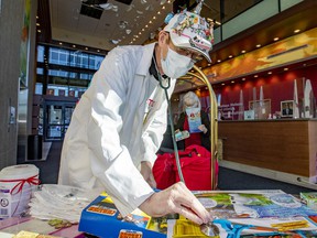 Toy Doctor Norman Brown jokingly takes the pulse of gifts he gives to patients at the Shriners Hospital for Children in Montreal on Wednesday, Nov. 24, 2021.