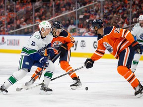 Jesse Puljujarvi (13) and Darnell Nurse (25) of the Edmonton Oilers battle Alex Chiasson (39) of the Vancouver Canucks at Rogers Place on October 13 in Edmonton.
