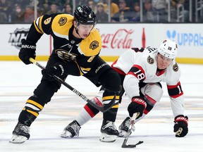 Mike Reilly of the Boston Bruins and Tim Stuetzle of the Ottawa Senators battle for control of the puck during the first period at TD Garden on November 9, 2021 in Boston.