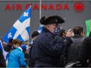 People attend a protest organized by the Société Saint-Jean-Baptiste in front of Air Canada headquarters in Montreal on Saturday, November 13, 2021, to denounce the airline's board of directors for keeping CEO Michael Rousseau in his charge despite his disability.  speak french. 