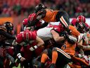 BC Lions Jordan Williams, top right, leaps over the pile to try and stop Calgary Stampeders quarterback Jake Maier from returning as he carries the ball during a short first down in the first half on Friday. 