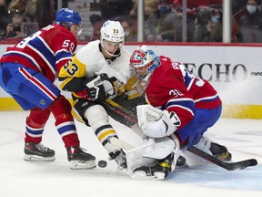 Teddy Bluger of the Pittsburgh Penguins stands between Montreal Canadiens defender Mattias Norlinder and goalkeeper Cayden Primeau during the second period in Montreal on Thursday, Nov. 18, 2021.