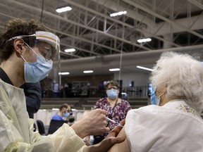 A healthcare worker gives a COVID-19 vaccine to Marion Locke at the Bill Durnan Arena in March 2021.