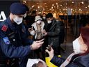 Police officers check shoppers' vaccination status at a store entrance in Vienna on Tuesday, November 16, 2021 after the Austrian government imposed a lockdown on approximately two million people who are not fully vaccinated against COVID- 19.