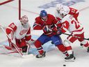 Christian Dvorak of the Montreal Canadiens fights for the puck against Detroit Red Wings goalkeeper Alex Nedeljkovic as Pius Suter and Filip Hronek enter the play during the first period in Montreal on November 2, 2021. 
