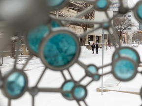 Pedestrians navigate the snowy sidewalks on 108th Street as they pass a snowy Firebrand Glass, a collaboration between award-winning artists Julia Reimer and Tyler Rock, near the Alberta Legislature in Edmonton, Tuesday, Nov. 16, 2021. The region of the capital has been affected by the first major snow storm of the season.  Photo by Ian Kucerak