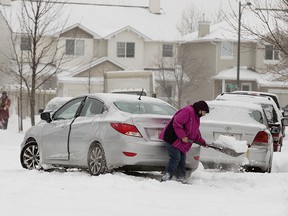 A motorist excavates his vehicle near 34 Avenue and Tamarack Green, in Edmonton, on Tuesday, November 16, 2021. The phase 1 parking ban will begin at 7 p.m. and will remain in effect until the city has cleared major roads, like arteries and collector roads.  as well as highways, bus routes and roads with warning signs 