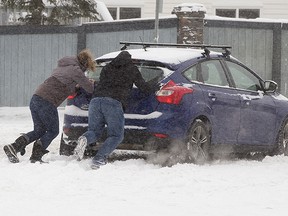 Good Samaritans push a motorist stuck at the intersection of 38th Avenue and 38th Street, in Edmonton, on Tuesday, November 16, 2021. The phase 1 parking ban will begin at 7 p.m. and will remain in effect until the city have cleared the main roads, such as the artery and the collector.  highways, as well as highways, bus routes, and roads with warning signs. 