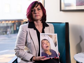 Heather Steinke-Attia holds up a photo of her client Pacey Dumas after he was hospitalized in late 2020. A lawsuit filed by Dumas and his family claims that Edmonton Police Const.  Ben Todd kicked him in the head during an arrest last December.  Dumas was never charged with any crime.