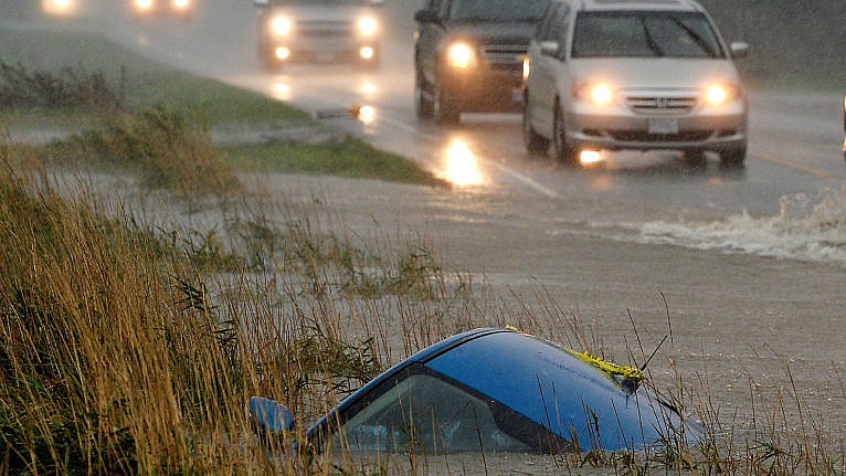 A car lies submerged in a ditch on a flooded stretch of road after storms hit the western Canadian province of British Columbia, causing landslides and flooding, closing roads, in Chilliwack, British Columbia, Canada, on November 15, 2021 (Jennifer Gauthier / Reuters).