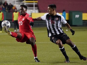 Jonathan David (20) of Team Canada takes control of the ball while eluding Orlando Calderón (14) of Team Costa Rica during a 2022 FIFA World Cup qualifying soccer match held at Commonwealth Stadium in Edmonton.