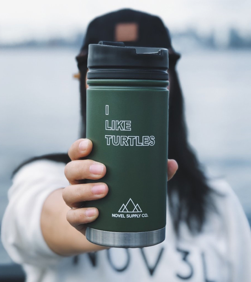 A photo of a person holding a green coffee mug that says "I like turtles"