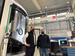 Donny Butler (left) and his brother Kevin Butler (right), co-owners of Lakeshore-based tool and mold company CNCTech.com, stand in front of one of the automated fabrication machines in their shop.  Photographed on November 16, 2021.
