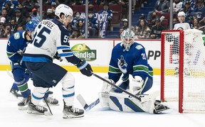 Winnipeg Jets' Mark Scheifele tries to put his stick on the loose puck after Vancouver Canucks goalkeeper Thatcher Demko makes a first-period stop at Rogers Arena on Friday night.