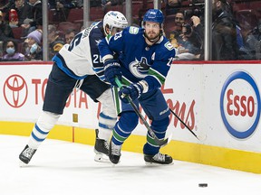 Oliver Ekman-Larsson of the Vancouver Canucks picks up the loose puck after breaking free from Blake Wheeler of the Winnipeg Jets in the first period at Rogers Arena on Friday night.