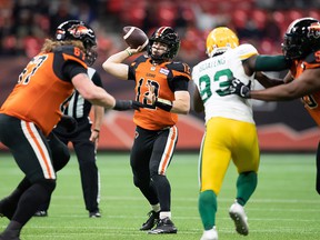 BC Lions quarterback Nathan Rourke passes as Phillip Norman stops Edmonton Elks' Kwaku Boateng during the first half at BC Place Stadium on Friday night.