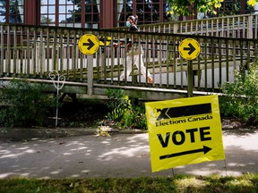 A woman walks past an Elections Canada sign at a polling station during Canada's federal elections in Toronto on September 20, 2021.