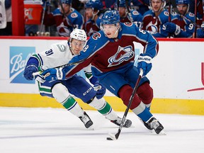 Colorado Avalanche defender Cale Makar controls the puck under pressure from Vancouver Canucks right wing Juho Lammikko in the first period at Ball Arena.