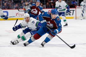 Colorado Avalanche defender Bowen Byram controls the puck ahead of Vancouver Canucks left wing Tanner Pearson in the first period at Ball Arena.