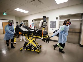 Paramedics and healthcare workers transfer a patient from the Humber River Hospital Intensive Care Unit to an air ambulance as the hospital clears space in its ICU unit, in Toronto, Ontario, Canada on April 28, 2021 .