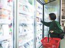 A young woman shops in the freezer aisle of a supermarket.  In the early days of commercial frozen foods, peas were marketed as 