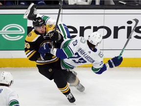 Brad Marchand (63) of the Boston Bruins checks Oliver Ekman-Larsson (23) of the Vancouver Canucks during the first period of an NHL hockey game, Sunday, Nov. 28, 2021, in Boston.