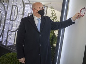Mayor Drew Dilkens places a heart on a magnetic wall next to the word HOPE, after making a tap donation that goes to the Windsor Regional Hospital Foundation and the Hotel-Dieu Grace Health Care Foundation, a new feature at this year's Bright Lights festival in Jackson Park, Thursday, Nov. 18, 2021.