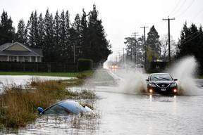 A car sits in a ditch on a flooded stretch of road in Chilliwack, on November 15, 2021.
