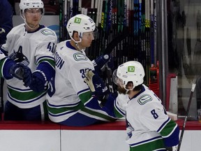 Winger Conor Garland skates on the Canucks bench, being congratulated by his teammates, including Elias Pettersson (left) with whom he has found some chemistry on the ice lately, albeit in a brief taste.