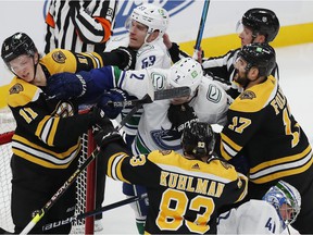 Trent Frederic (11) of the Boston Bruins fights Bo Horvat (53) and Luke Schenn (2) of the Vancouver Canucks during the second period of an NHL hockey game, Sunday, Nov. 28, 2021, in Boston.