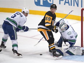 Jake Guentzel (59) of the Pittsburgh Penguins can't find a rebound off Vancouver Canucks goalkeeper Thatcher Demko (35) with Tucker Poolman (5) defending during the first period of an NHL hockey game in Pittsburgh on Wednesday November 24.  2021.