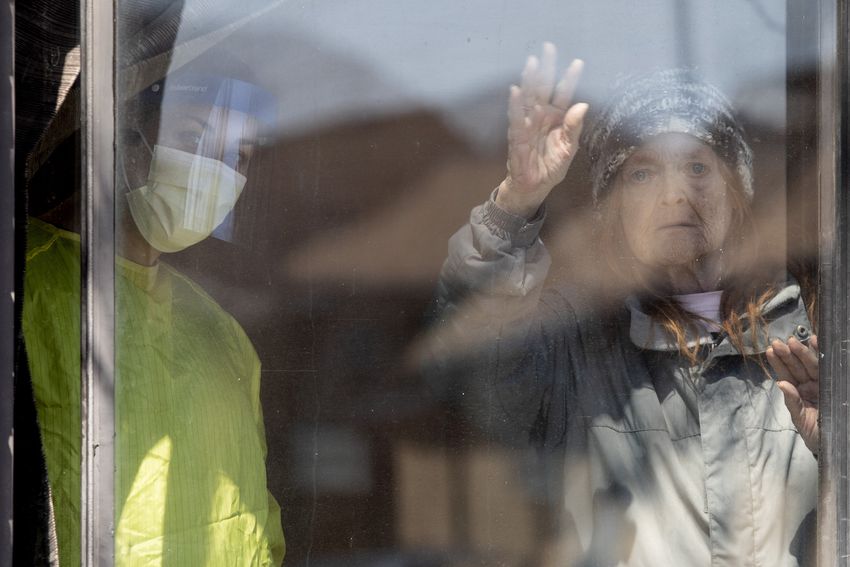 A resident named Joyce greets as she stands with a staff member to watch supporters drive past the Orchard Villa Care home in Pickering, Ontario.  on Saturday, April 25, 2020.