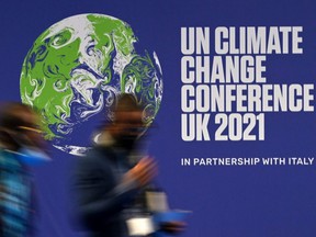 Delegates pass a poster for the United Nations Climate Change Conference in the United Kingdom 2021, during the COP26 summit in Glasgow, Scotland, on Tuesday, November 2, 2021.