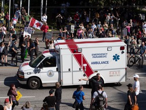 FILE PHOTO: An ambulance drives through a crowd of people protesting passports for the COVID-19 vaccine and mandatory vaccinations for healthcare workers in Vancouver earlier this month.