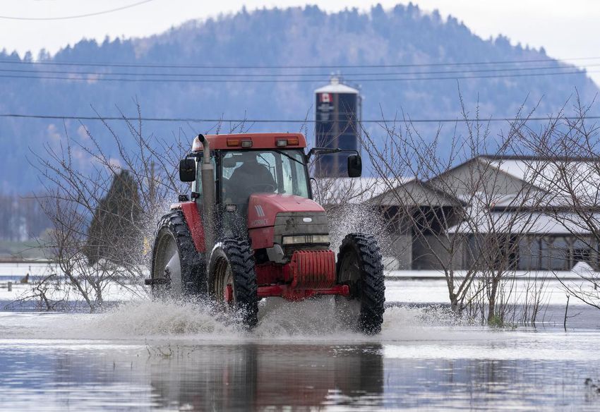 A tractor passes a flooded road caused by heavy rain and landslides earlier in the week in Abbotsford.