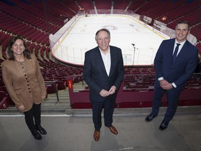 Quebec Prime Minister François Legault is flanked by Isabelle Charest, the CAQ's key person in sports, and former NHL goalkeeper Marc Denis at the Bell Center on Thursday.