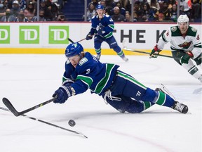 Vancouver Canucks' Jack Rathbone stumbles when reaching for the puck during the first period of an NHL hockey game against Minnesota Wild in Vancouver, Tuesday, Oct. 26, 2021.