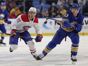 Canadiens' Jake Evans (71) watches Sabers defender Mark Pysyk (13) hit the puck with his stick at the KeyBank Center in Buffalo on Friday, Nov. 26, 2021.