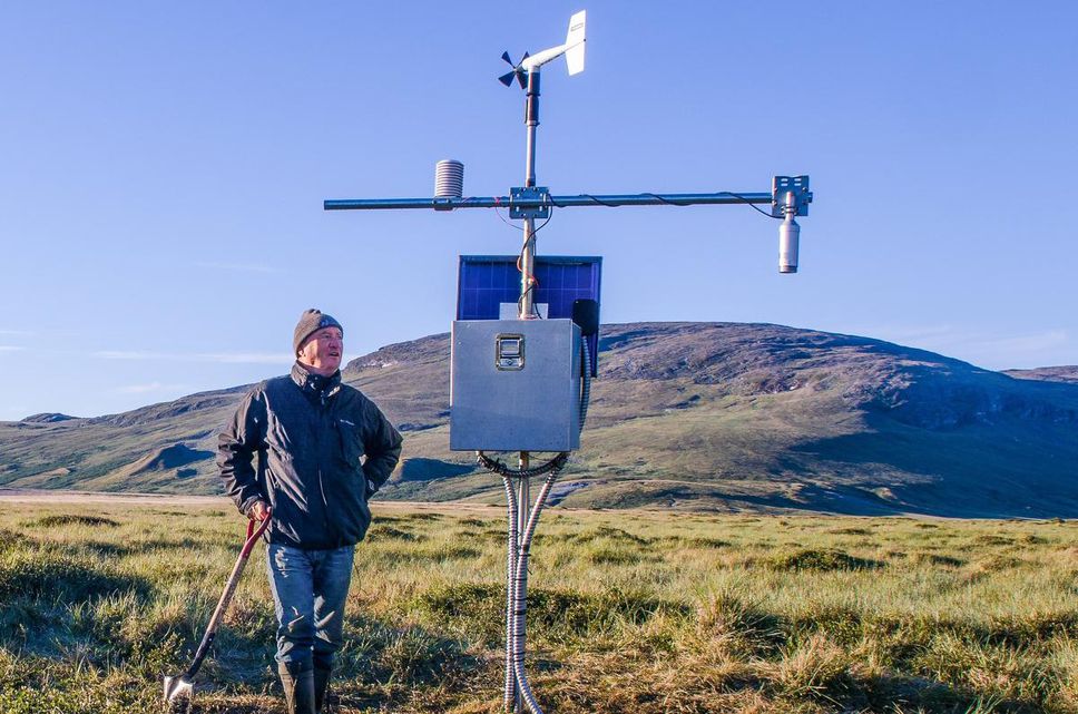 Michel Allard, a professor emeritus at the University of Laval, looks at one of his sensors deployed at Salluit in Nunavik in this photo from the 2016 brochure.