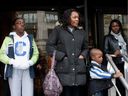 Casey Fuh-Cham, 12, left to right, her mother Yvette Fuh-Cham and younger brother Andy Fuh-Cham, four, wait with supporters on the step of federal court in Montreal on Tuesday, Oct. 7, 2014. The Fuh -The Cham family fears deportation back to Cameroon and was attending a hearing.