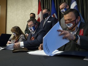 Prime Minister Jason Kenney (back center) watches as (left to right) Willow Lake Métis Nation President Stella Lavalee, Indian Relations Minister Rick Wilson, and Fort McKay Métis Nation President Ron Quintal , sign an agreement that will see the Alberta government award a $ 372,000 grant to Support the two Métis organizations in their fight against Bill C-48, in Edmonton, on Monday, November 15, 2021.