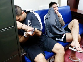 Arrested Canadian citizens James Clayton Riach (right) and Ali Memar Mortazavi Shirazi await their investigation procedure at the Justice Department in Manila, Philippines, on January 16, 2014.